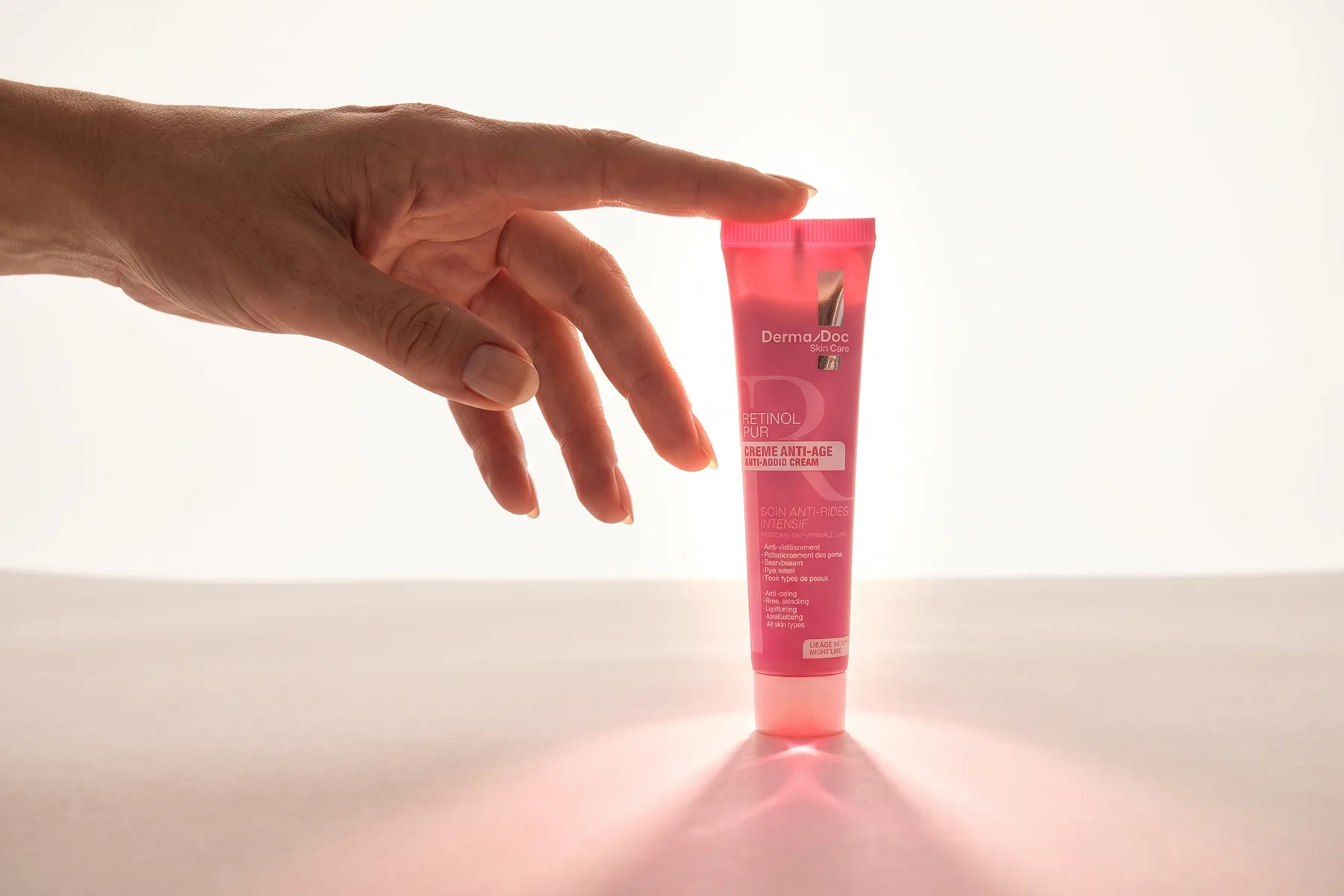 Une main s’approchant du Rétinol Pur Crème Anti-Âge DermaDoc, à contre-jour.